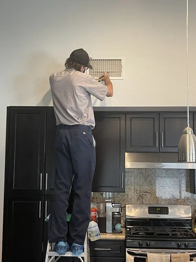 Technician inspecting an air vent during HVAC service in Grambling